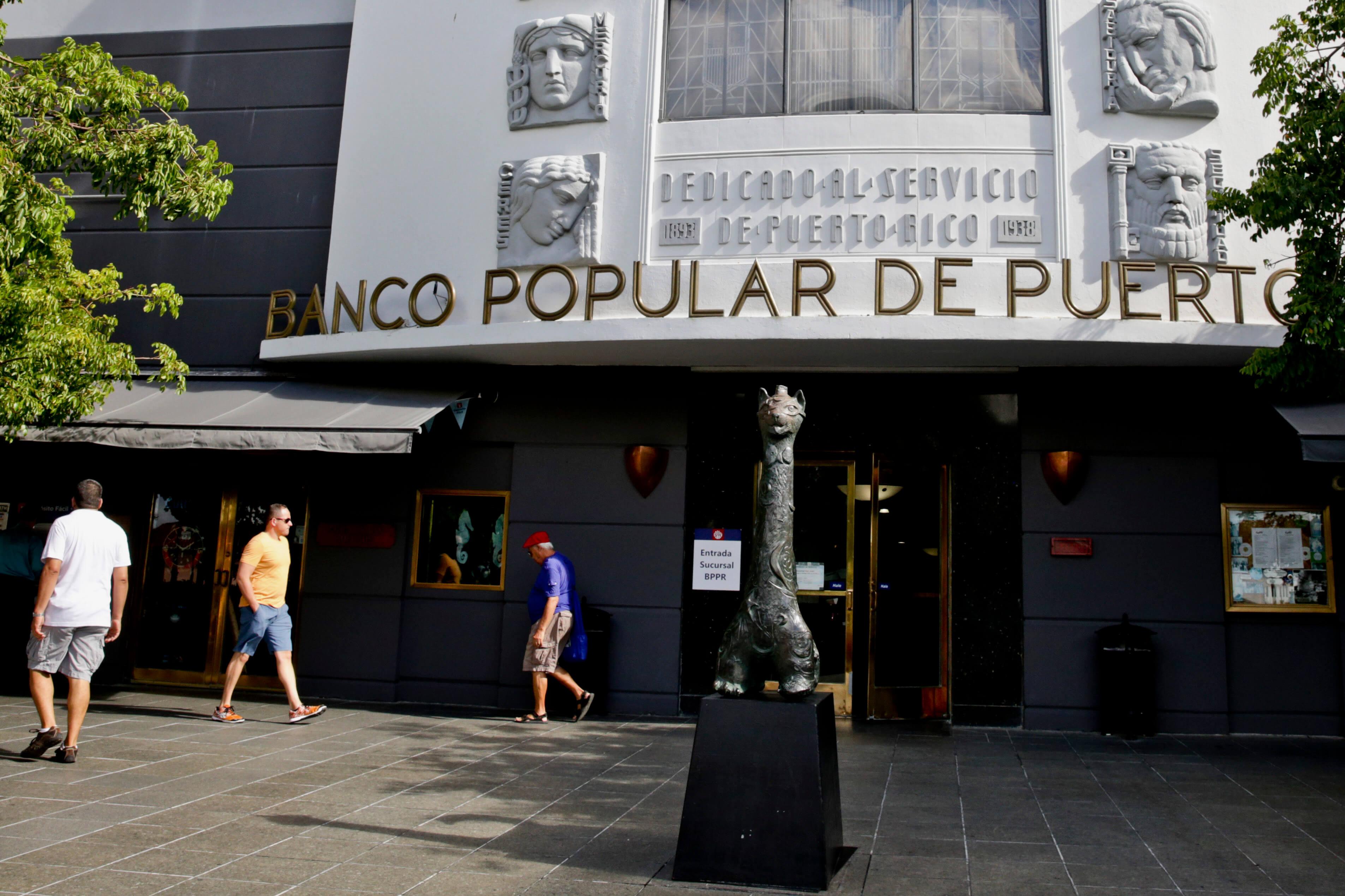 Fachada del Banco Popular de Puerto Rico con letrero dorado y relieves decorativos, personas caminando frente al edificio.
Derick E. Hingle/Bloomberg via Getty Images