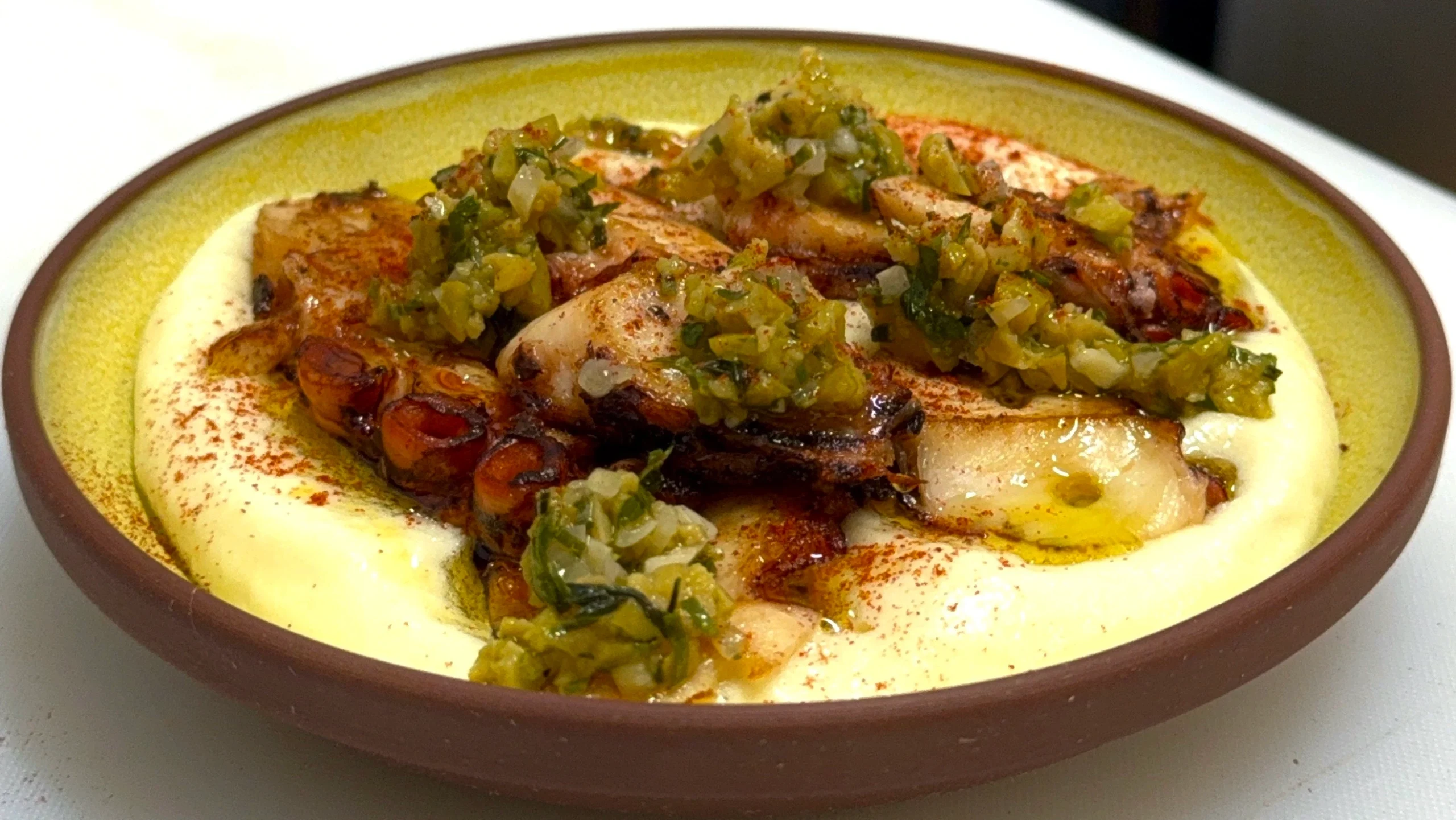 Pulpo español sobre foam de papa y apio con aceitunas Castelvetrano